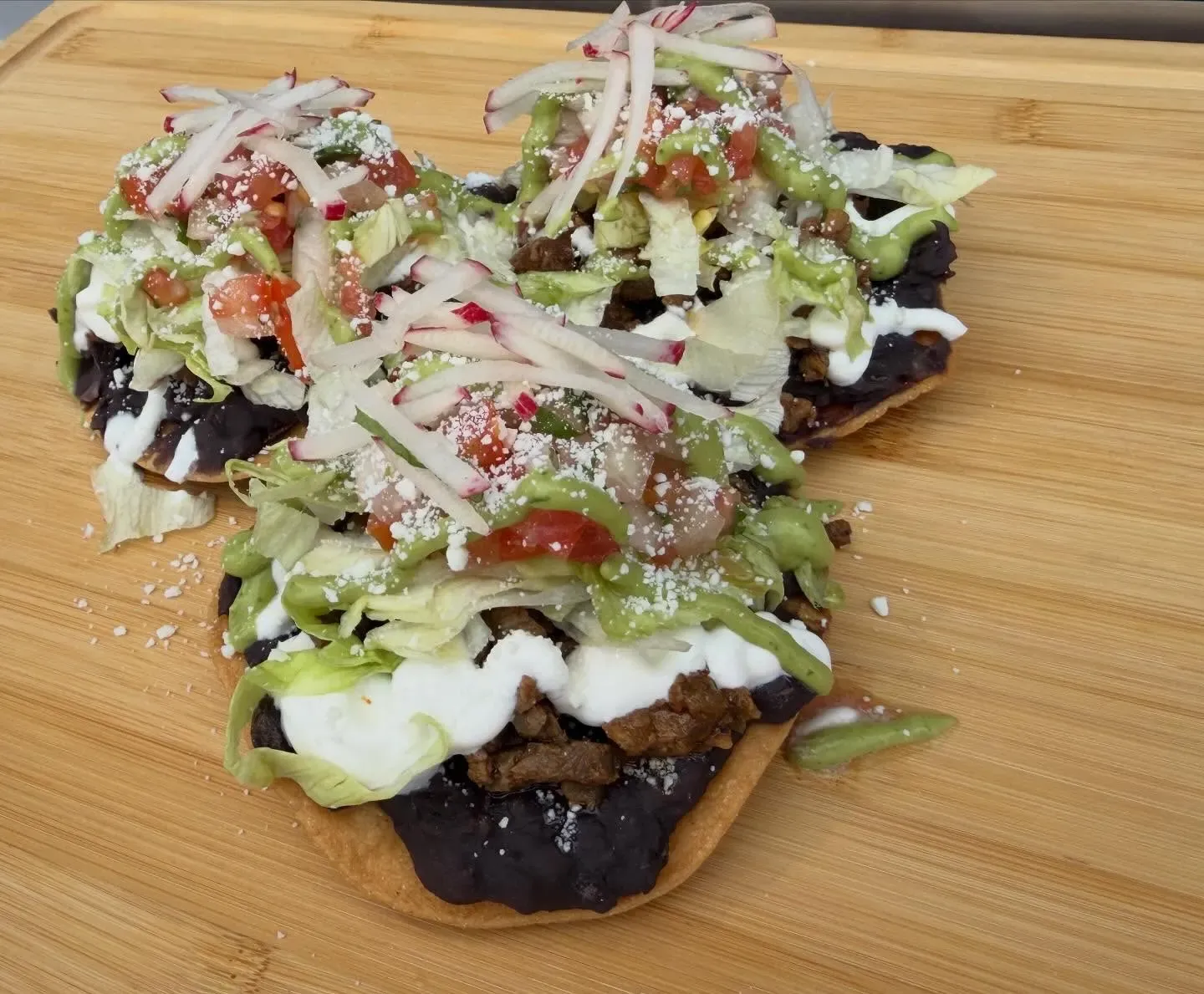 Three tostadas with black beans, radish and salsa verde